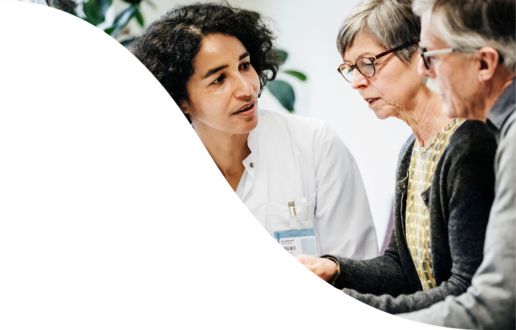 A clinical doctor giving some test results to a couple of elderly patients in hospital.